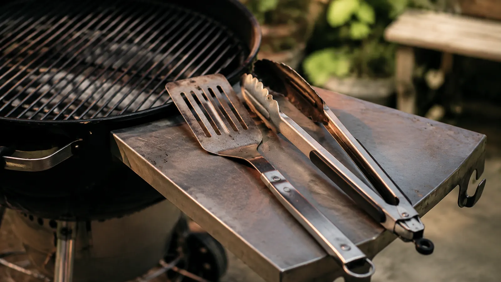 ROMANTICIST 23-piece BBQ grill accessories set laid out beside a charcoal kettle grill in a backyard